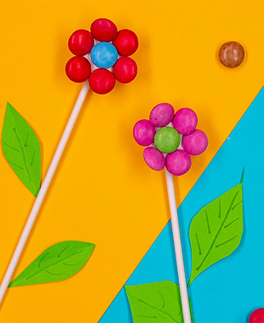Colourful Smarties stuck onto half a marshmallow on the end of a paper straw