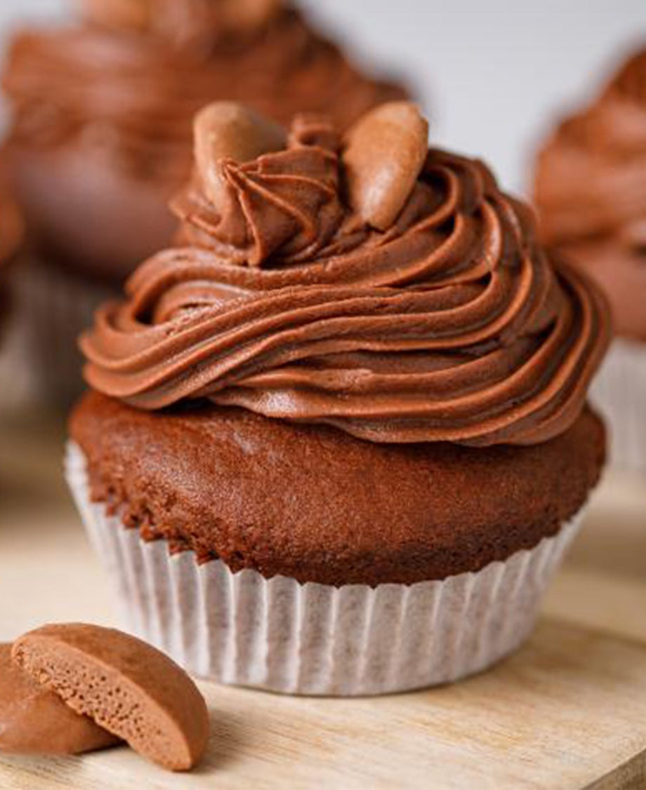 Close up of a chocolate cupcake with a swirl of chocolate buttercream on top dotted with Aero Melts