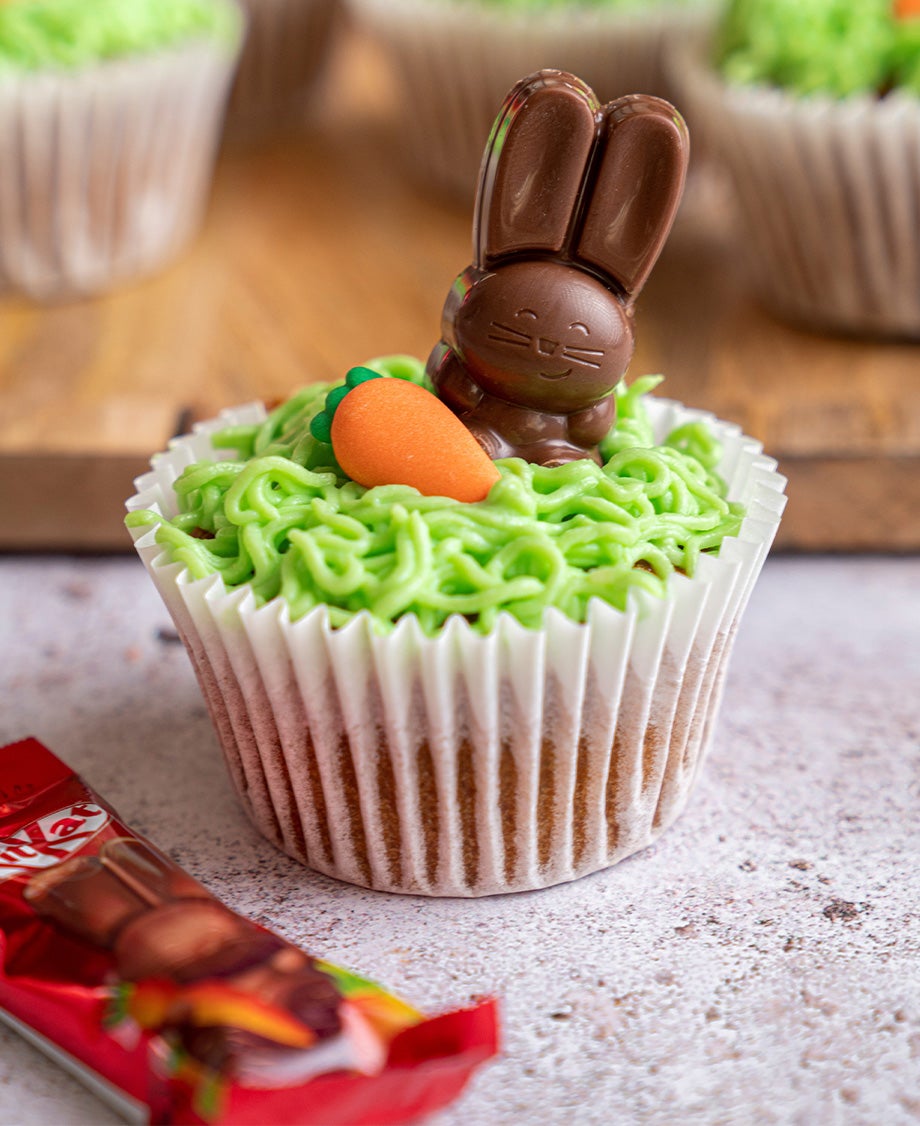 A close up of a cupcake with green buttercream icing and a chocolate KitKat bunny mini figure on top