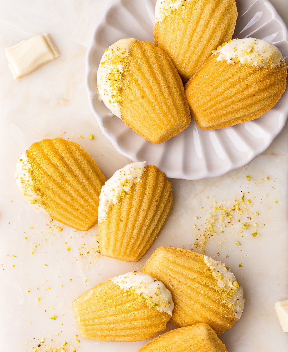 Milkybar-dipped madeleine cakes with pistachio crumb arranged in a mini beach scene