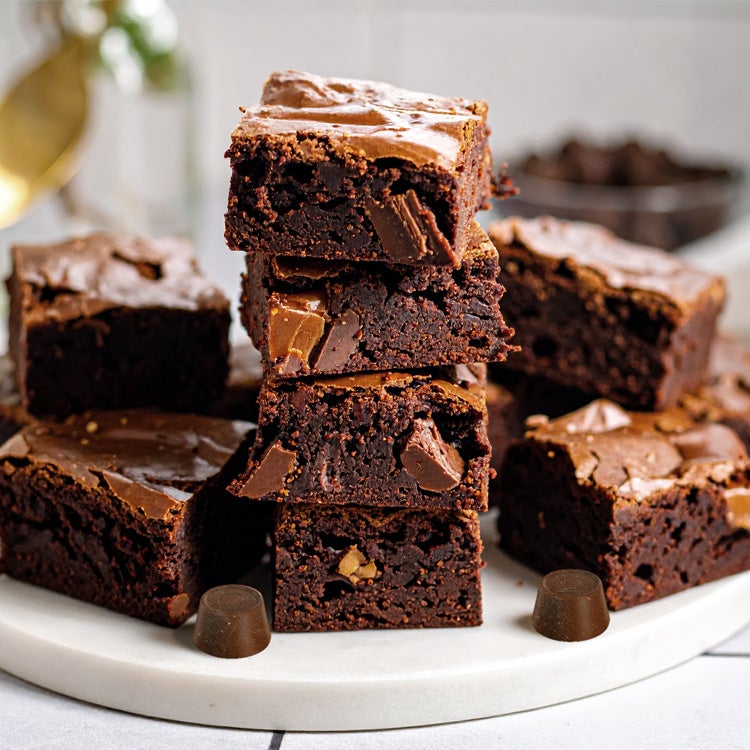 Stack of rich, fudgy Rolo salted caramel brownies with gooey caramel centres and chocolate chunks, served on a white plate