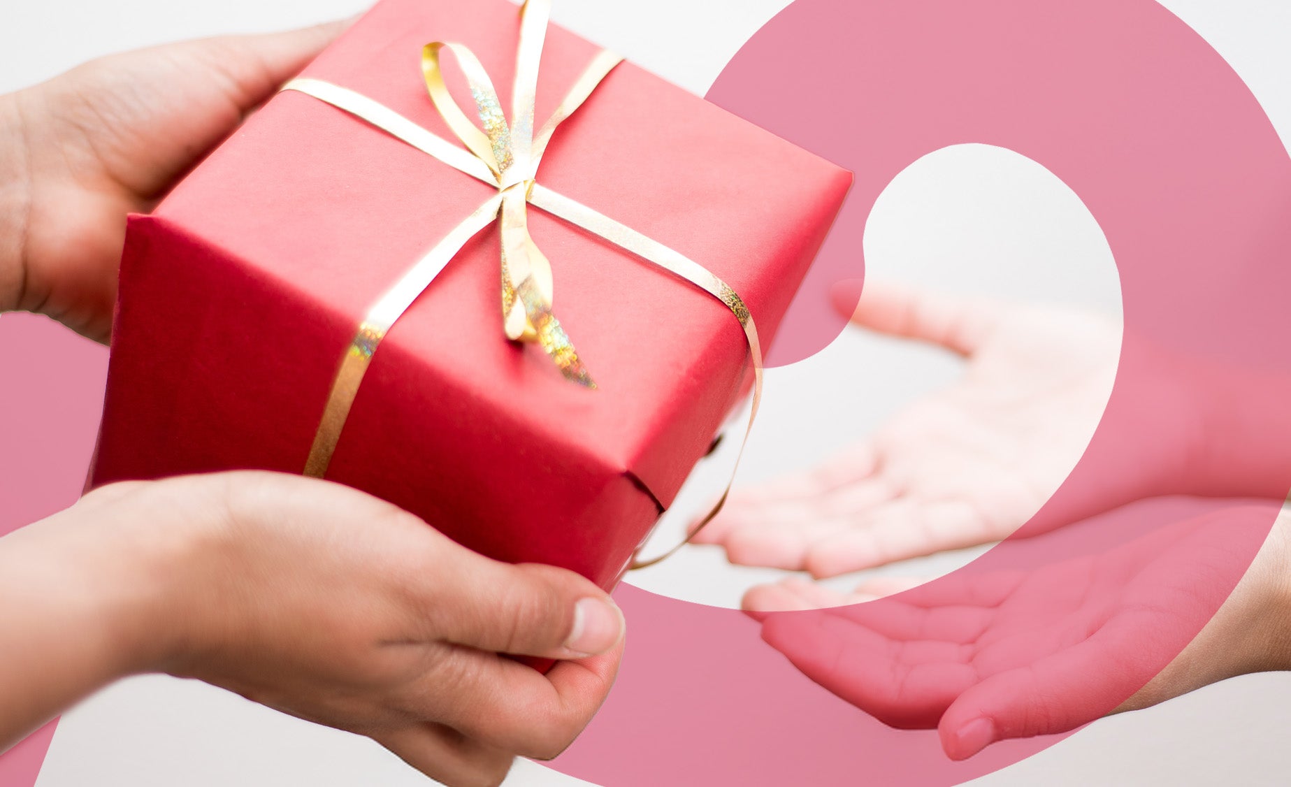 A pink parcel with gold paper ribbon decoration being passed from one set of children’s hands to another