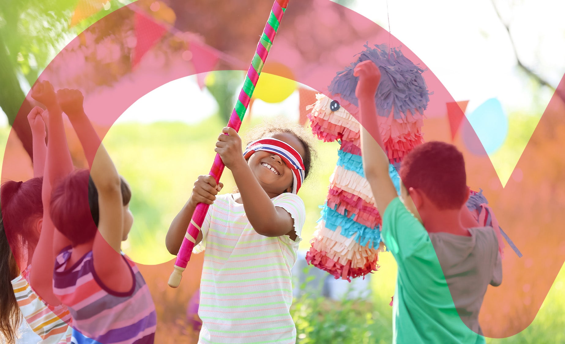 Group of children at an outdoor birthday party, with one blindfolded, hitting a horse-shaped pinata with a stripy stick.