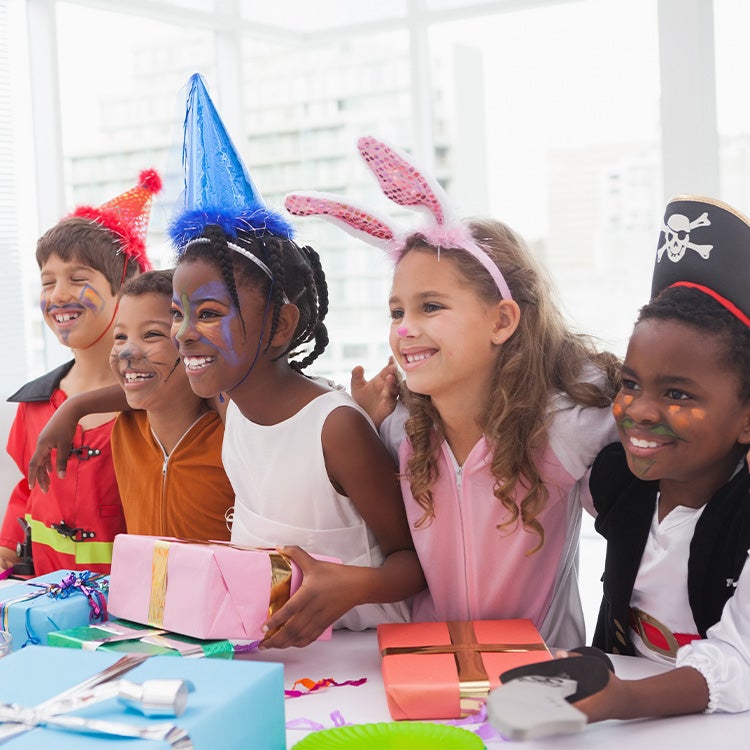 Group of children with face paint and fancy dress at a birthday party with white sofa in the background