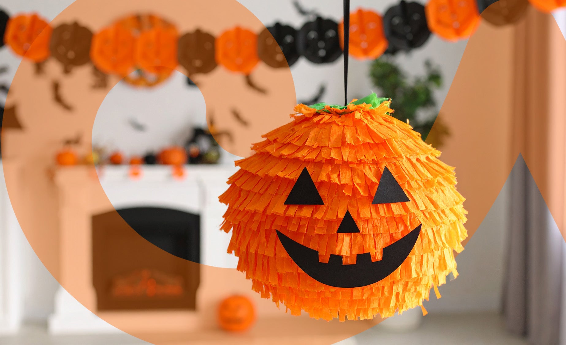 Pumpkin-themed pinata hanging from a ceiling with Halloween decorations in the background