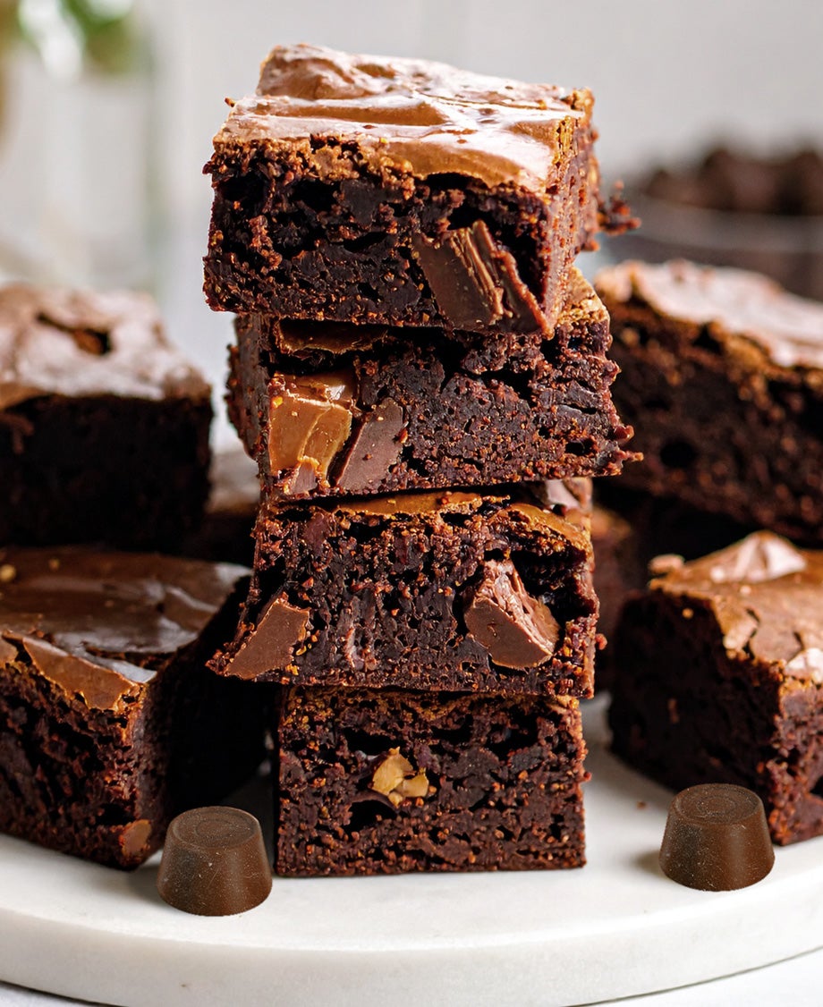 Stack of rich fudgy Rolo salted caramel brownies with gooey caramel centres and chocolate chunks, served on a white plate