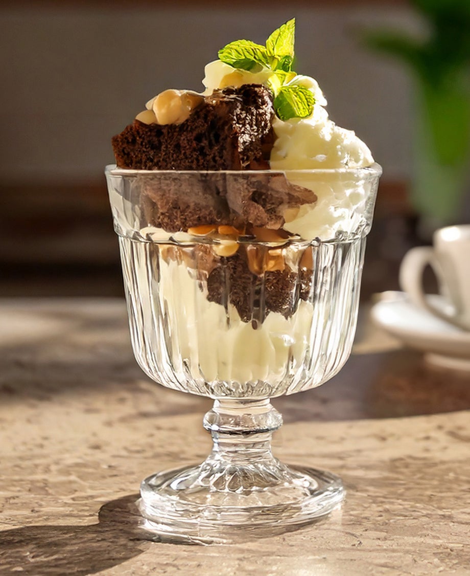Chocolate brownie sundae served in a transparent sundae glass made with vanilla ice cream, chocolate brownie, nuts and mint