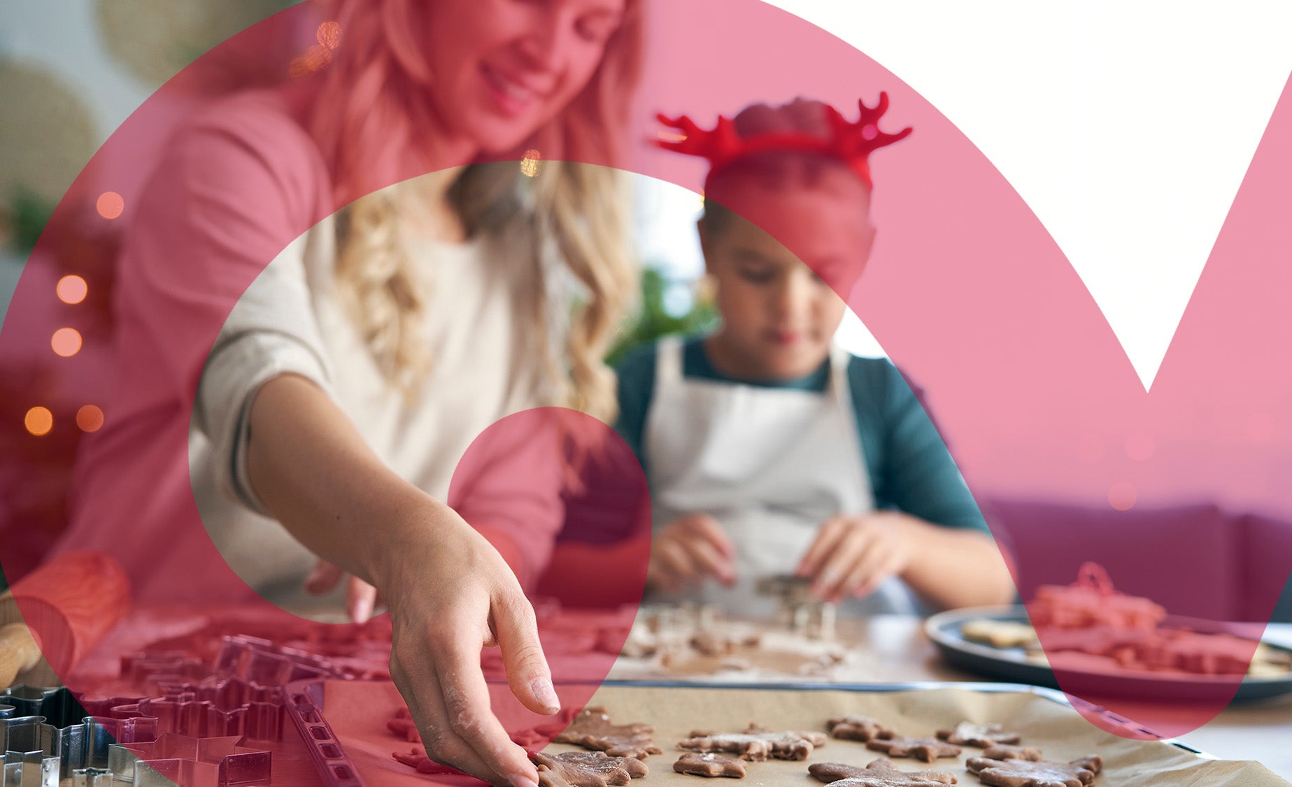 A woman and a child are joyfully baking cookies together in a cozy kitchen.