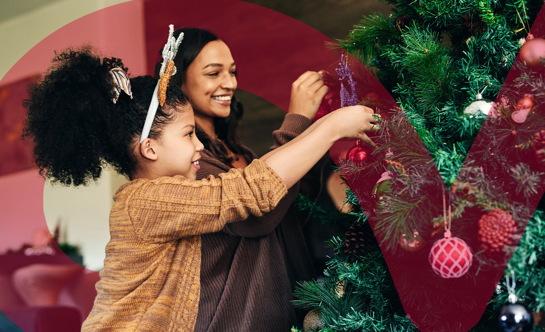 A mother and daughter joyfully decorate a Christmas tree with colorful ornaments and lights.