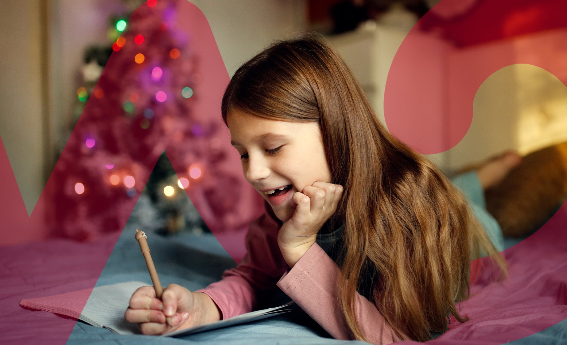 A girl writes on paper with a decorated Christmas tree in the background, creating a festive atmosphere.