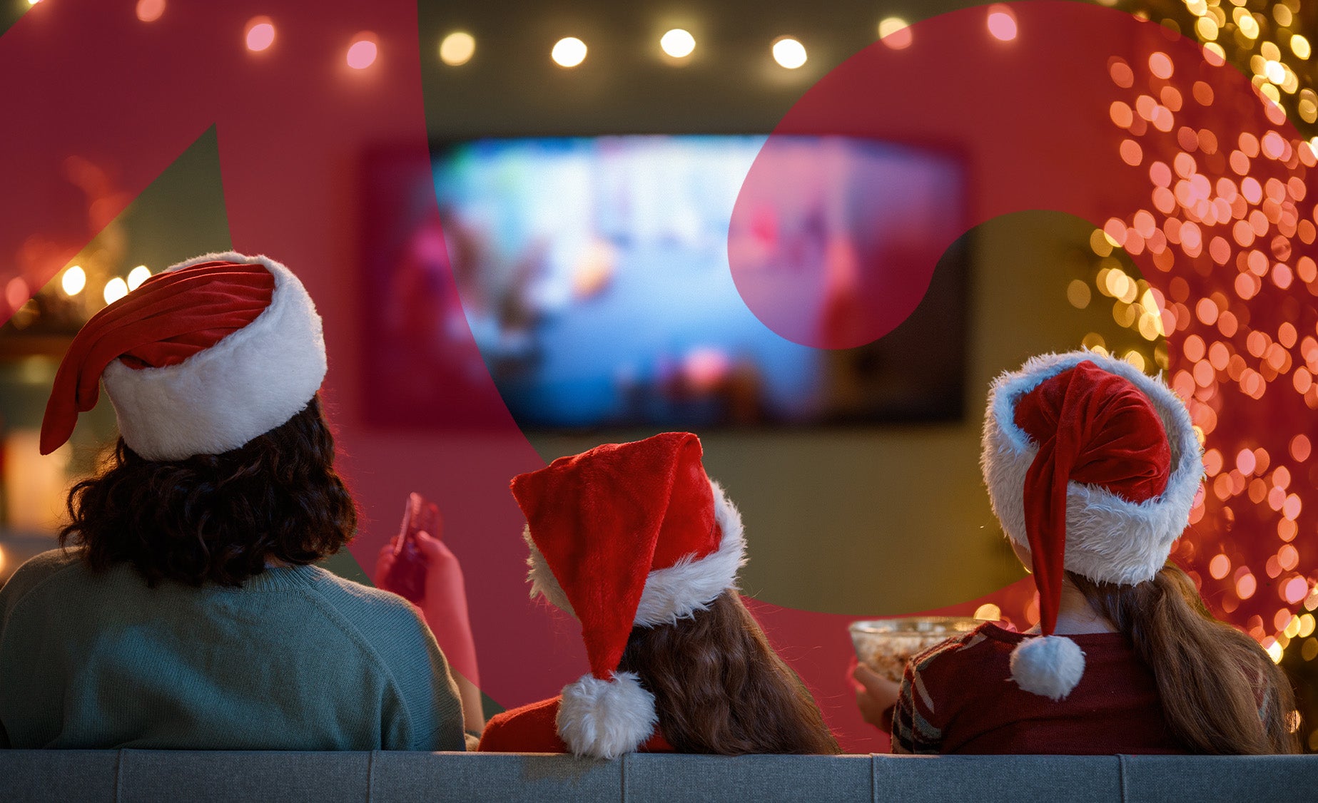 Three people in Santa hats watch TV, surrounded by colorful Christmas lights, enjoying a festive holiday atmosphere.