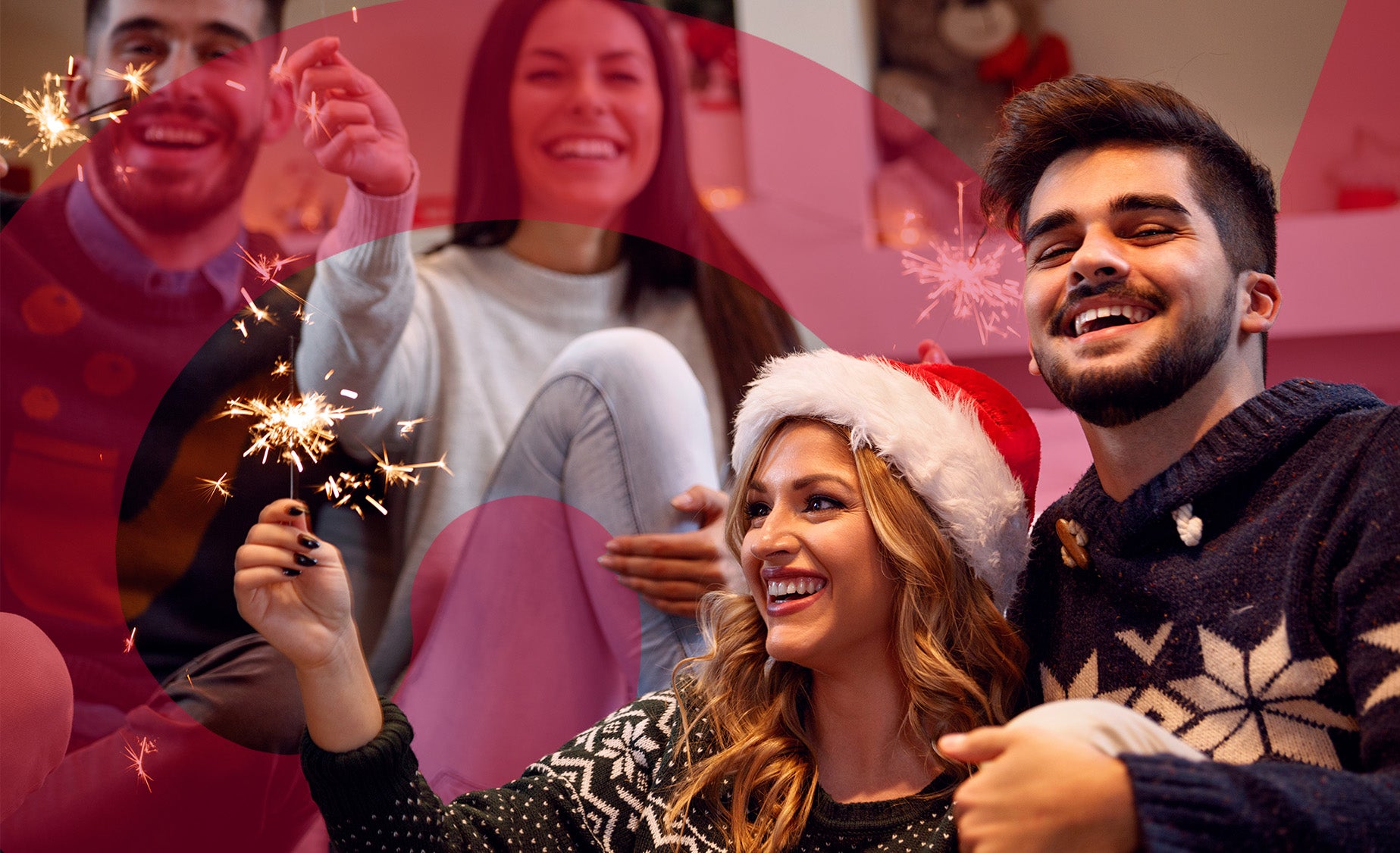 Group of friends in Christmas jumpers holding indoor sparklers and laughing