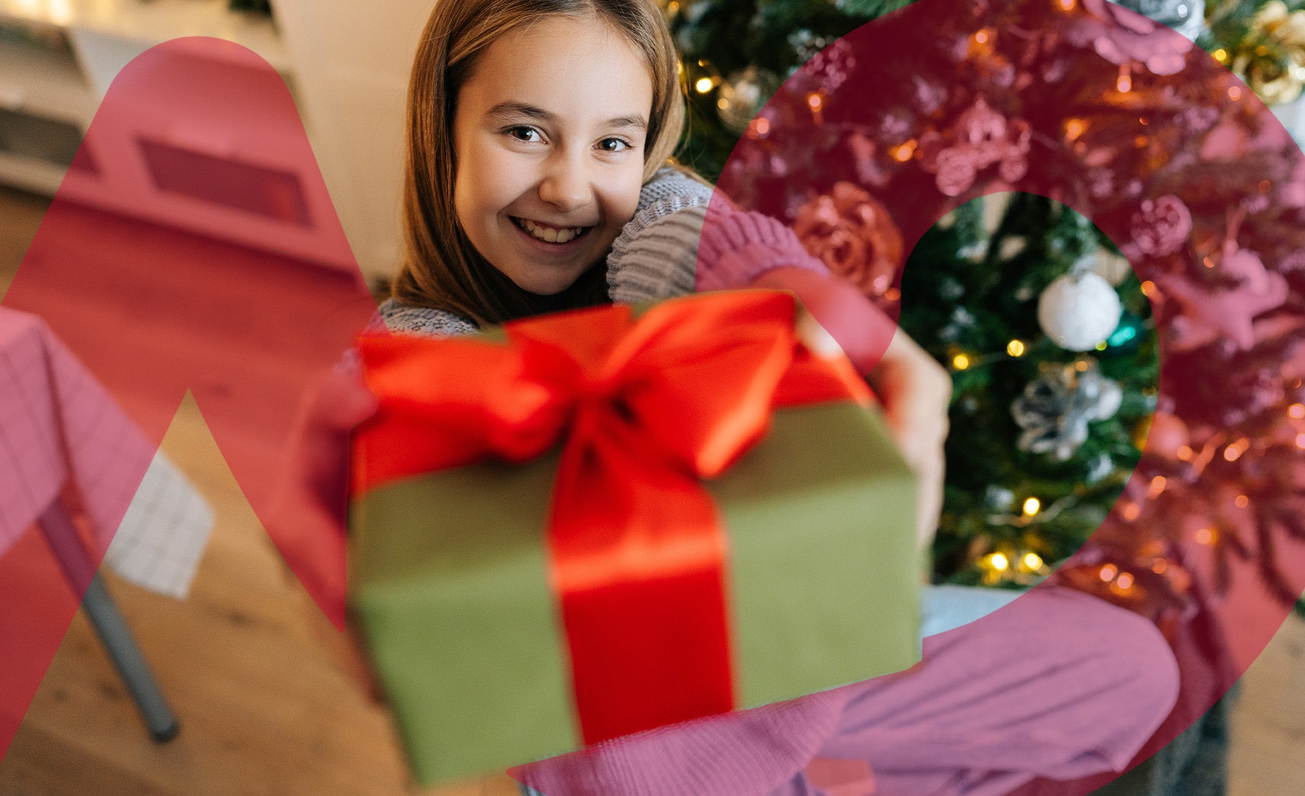 Girl passing a parcel to the viewer, with a Christmas tree in the background