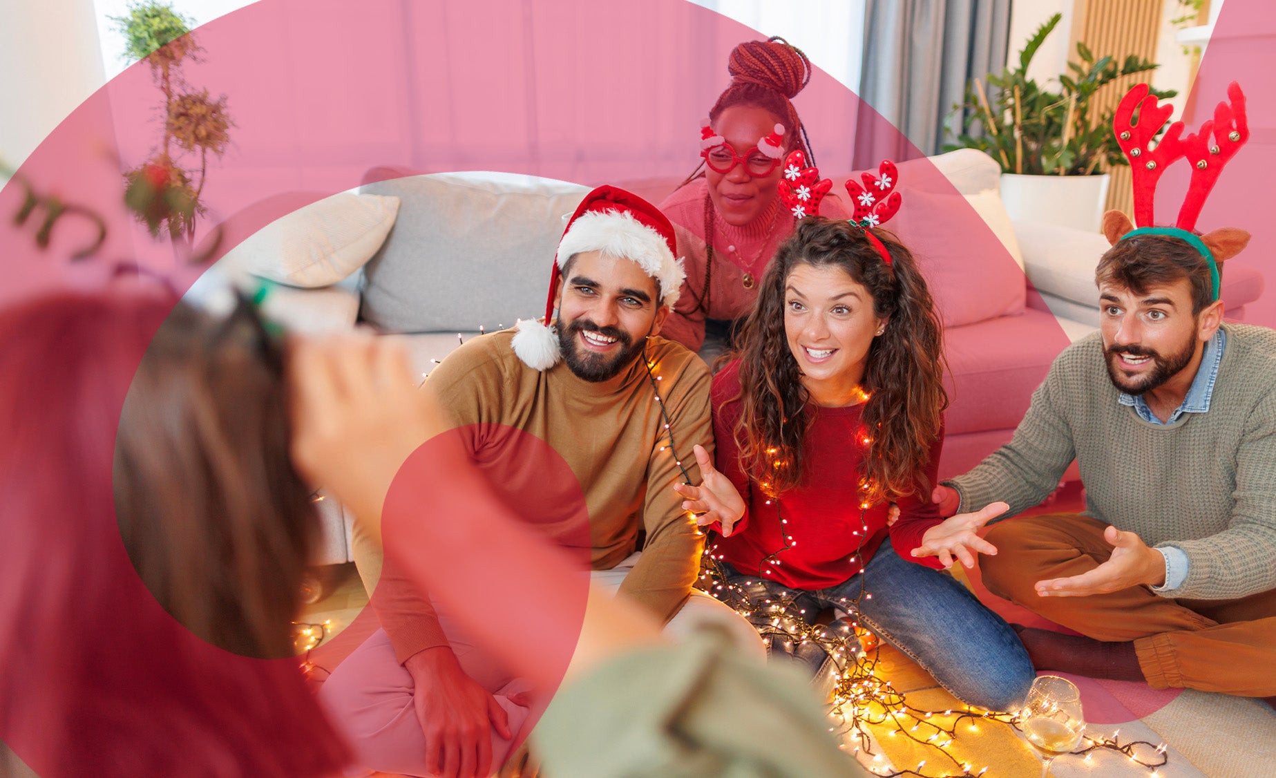 A group of friends playing a guessing game in a living room, wearing Christmas antlers