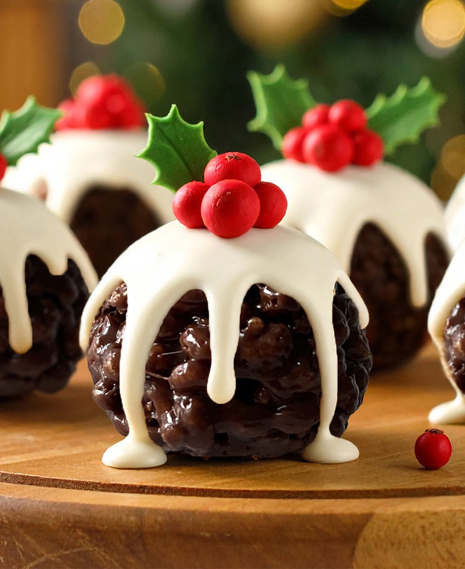 Round chocolate rice crispy balls decorated to look like mini Christmas puddings with dripping white chocolate icing plus red