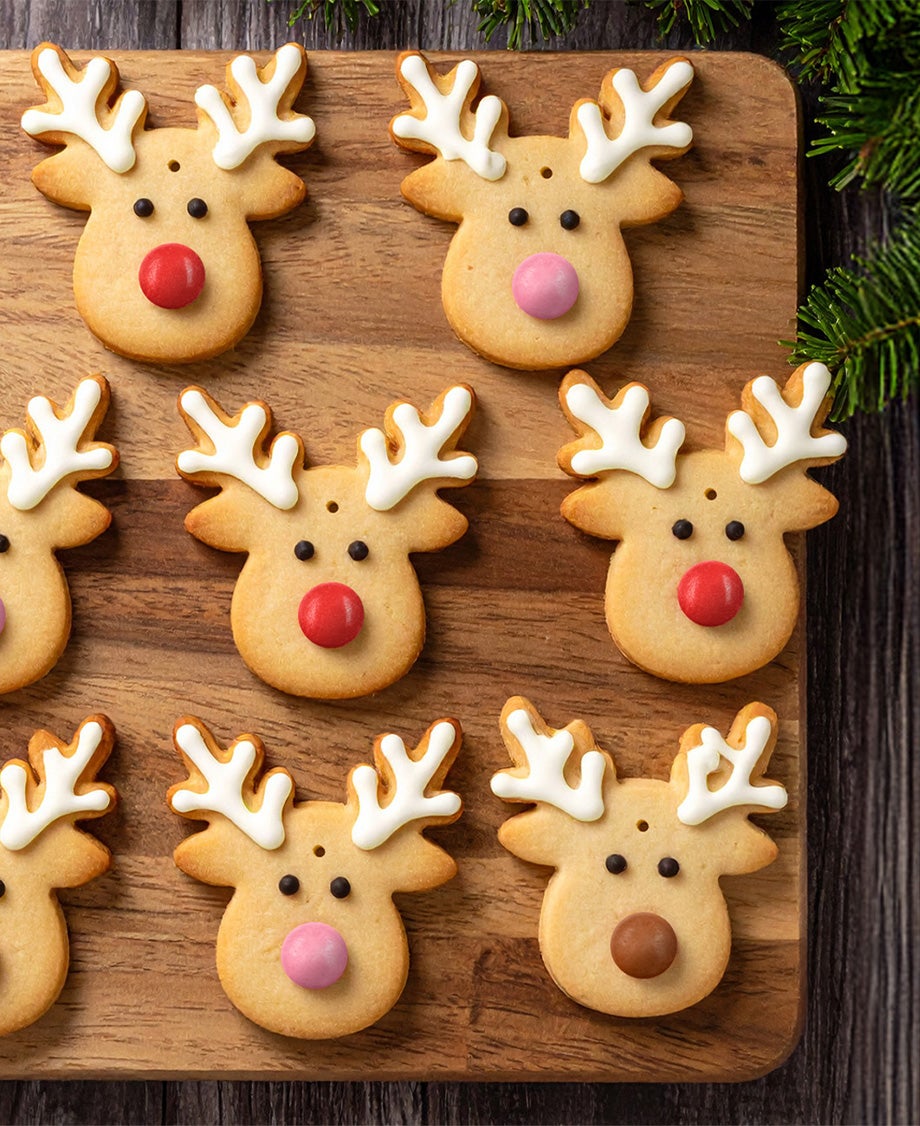 Golden reindeer cookies decorated with white icing on the antlers, black icing for the eyes, a red, pink or brown Smarties
