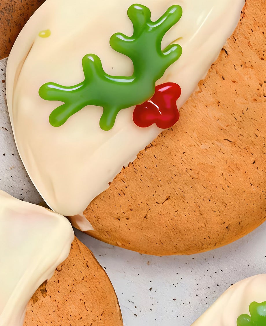 Round shortbread biscuits decorated to look like Christmas puddings using melted Milkybar white chocolate and gel icing