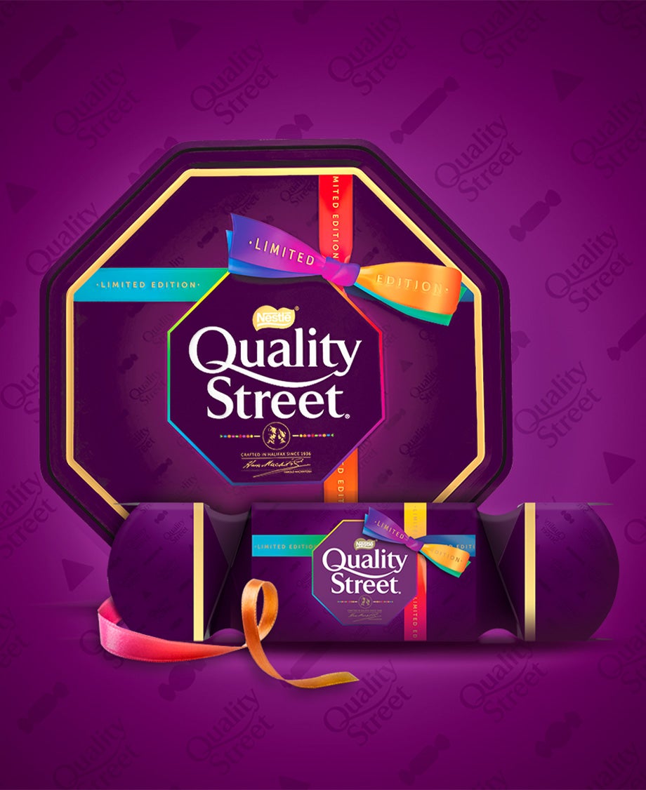 Quality Street tin and cracker arranged against a purple branded background