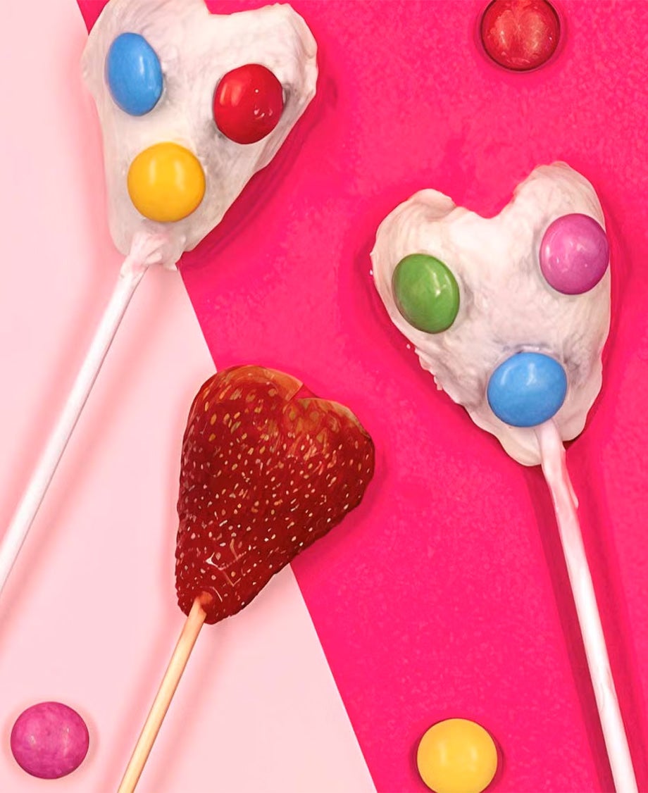 Strawberry halves on sticks dipped in Milkybar chocolate with Smarties stuck on to decorate 