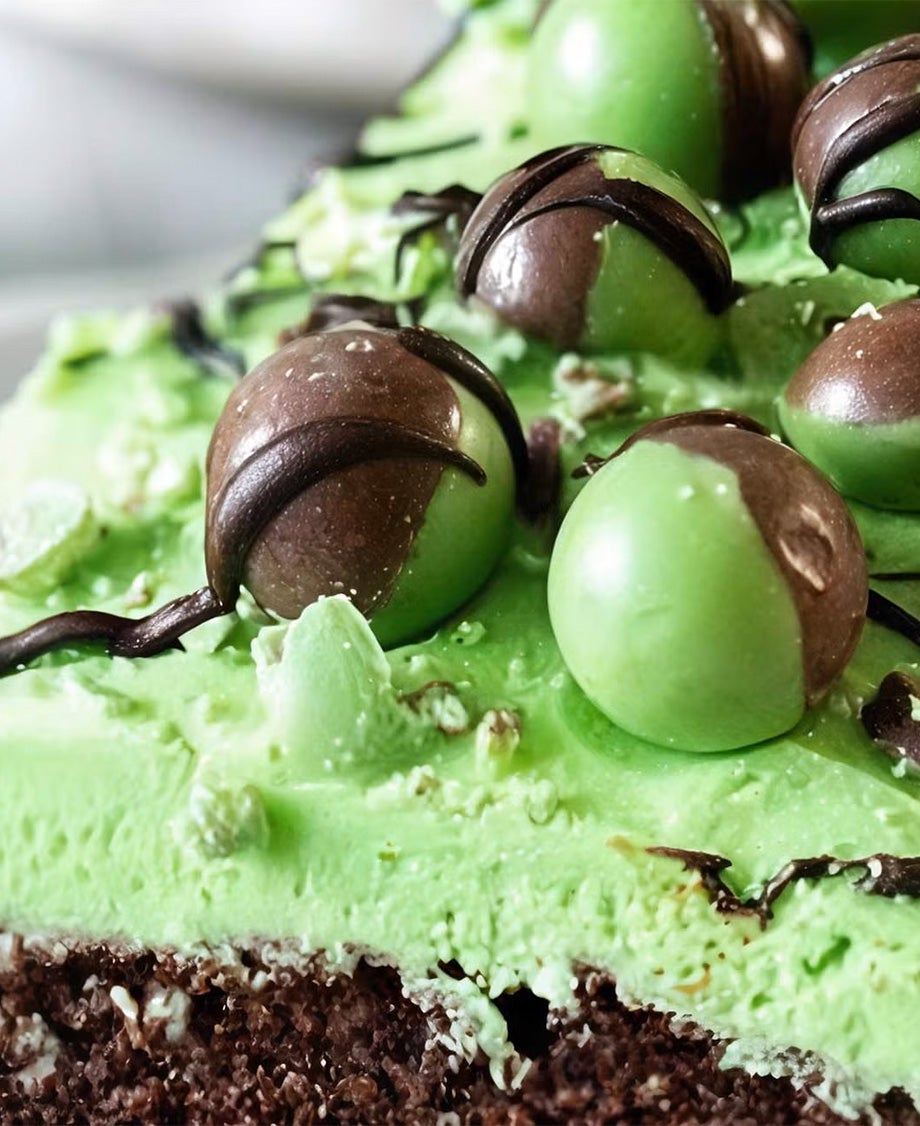 Dark chocolate cake topped with green cream frosting and Aero Peppermint Bubbles, drizzled with chocolate on a white plate