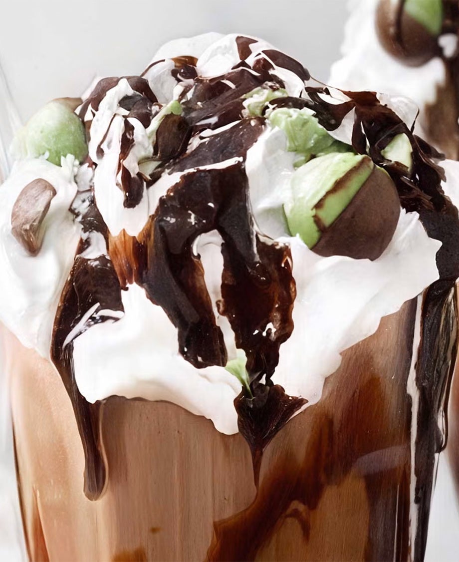 Close up of chocolate milkshake topped with whipped cream, decorated with chocolate sauce and Aero Peppermint Bubbles.