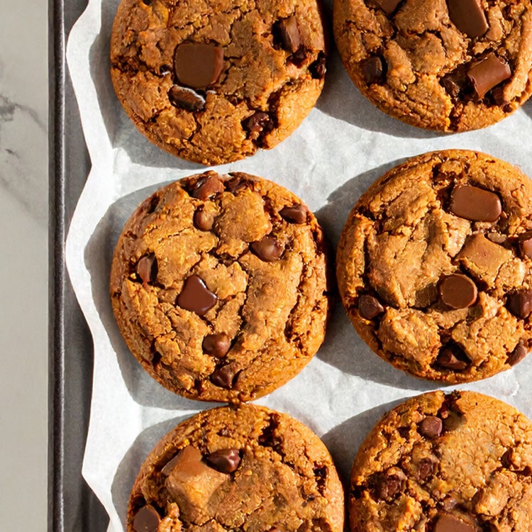 batch of 12 cookies studded wtih chunks of melted caramel Rolos cooling on a wire rack on some baking paper