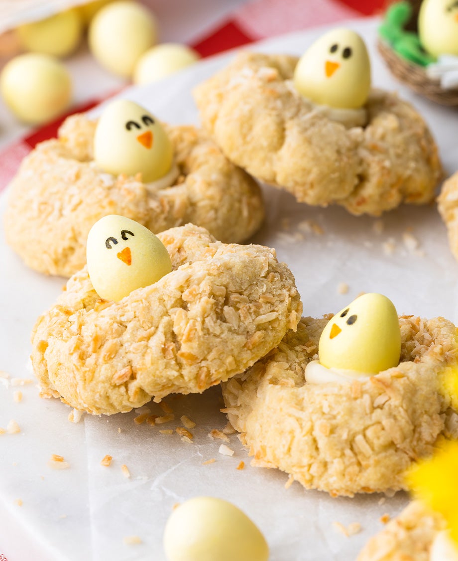 Golden coconut cookies decorated with a yellow Milkybar Mini Egg, with eyes and a beak painted on with edible pen