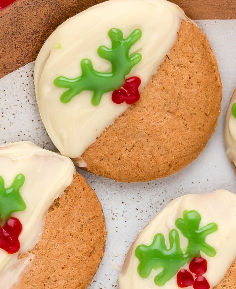 Christmas Biscuits decorated to look like Christmas puddings with melted Milkybar and Christmas holly and berry drawn on in e