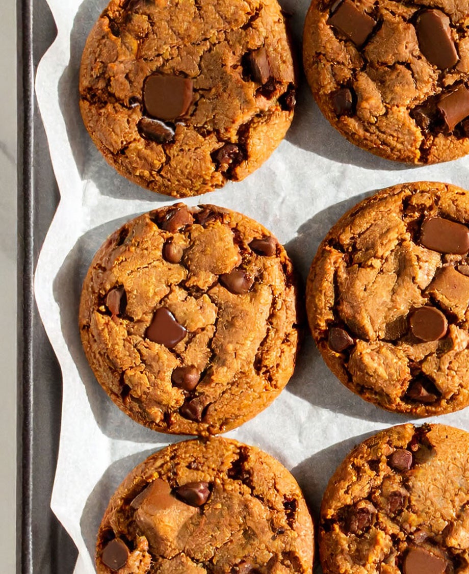 Golden cookies studded with Rolos on white baking paper on a tray