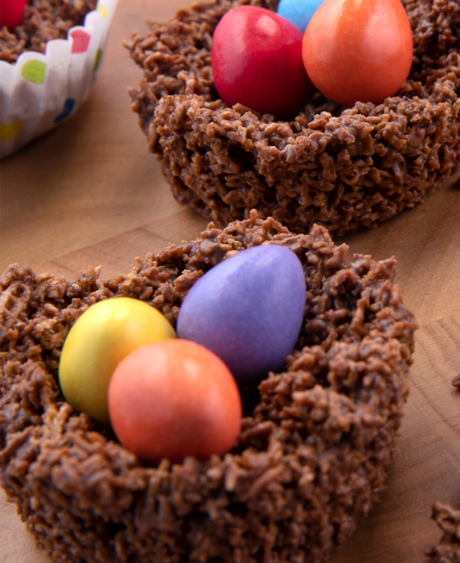 A chocolate cornflake nest with crushed cornflakes and three Smarties mini eggs in the centre. 