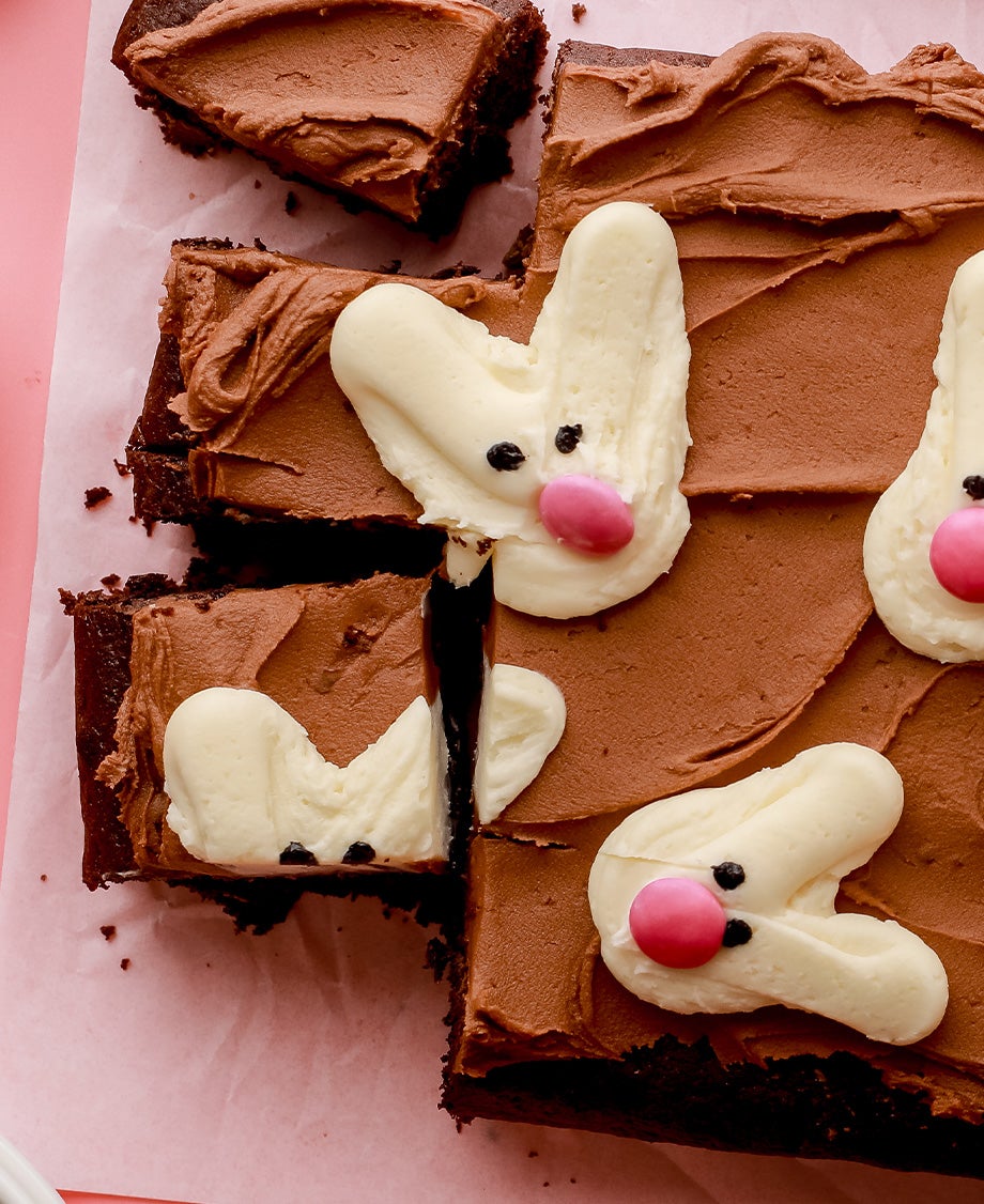  A brown, rectangular chocolate tray bake cake decorated with chocolate buttercream and piped-on white buttercream 