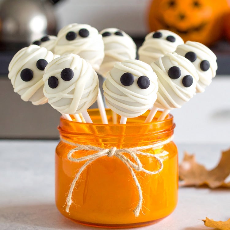 A jar showcasing colorful Halloween candy, featuring ghost-shaped cake pops for festive celebrations.