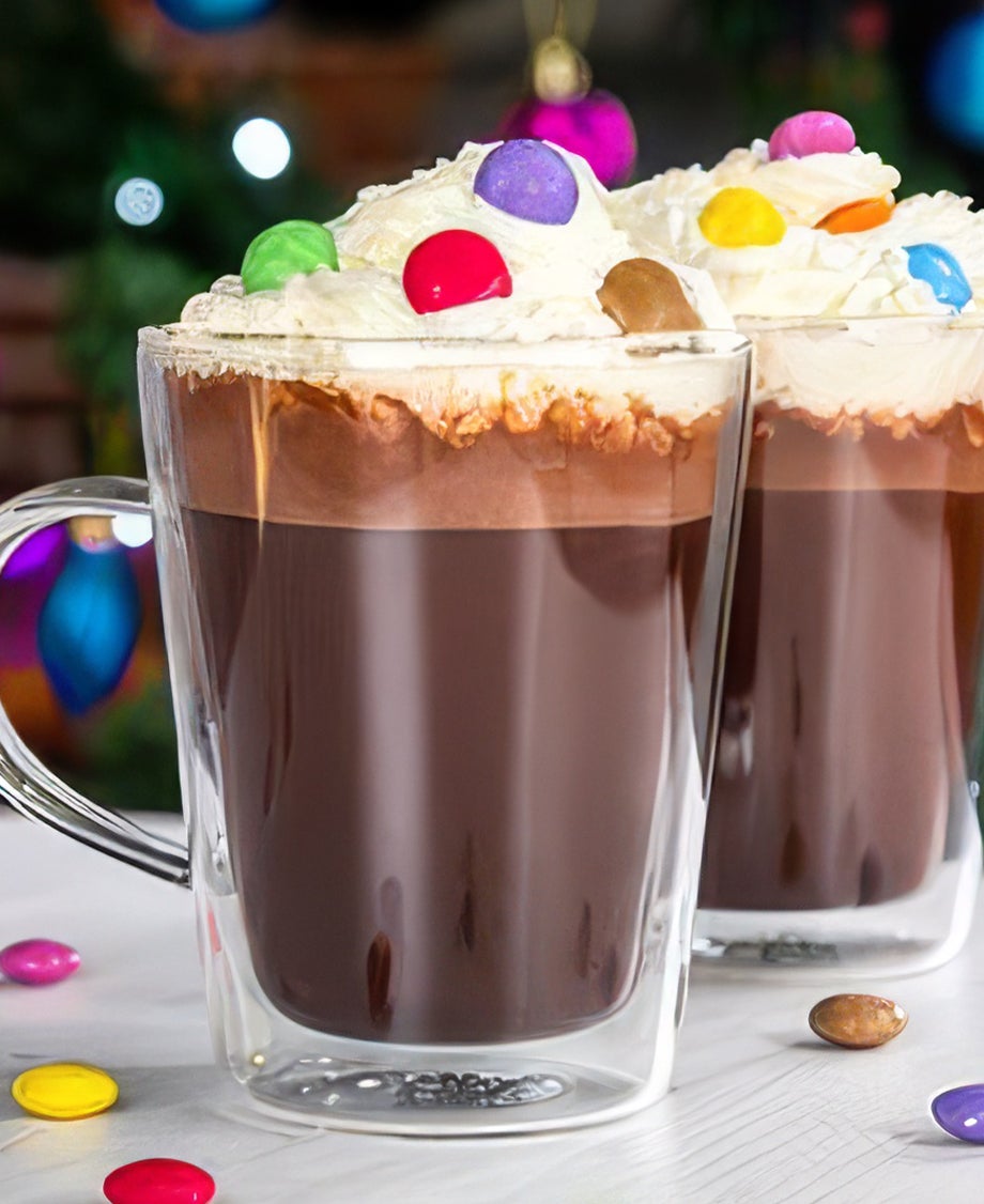 Two mugs of hot chocolate topped with whipped cream and colourful Smarties