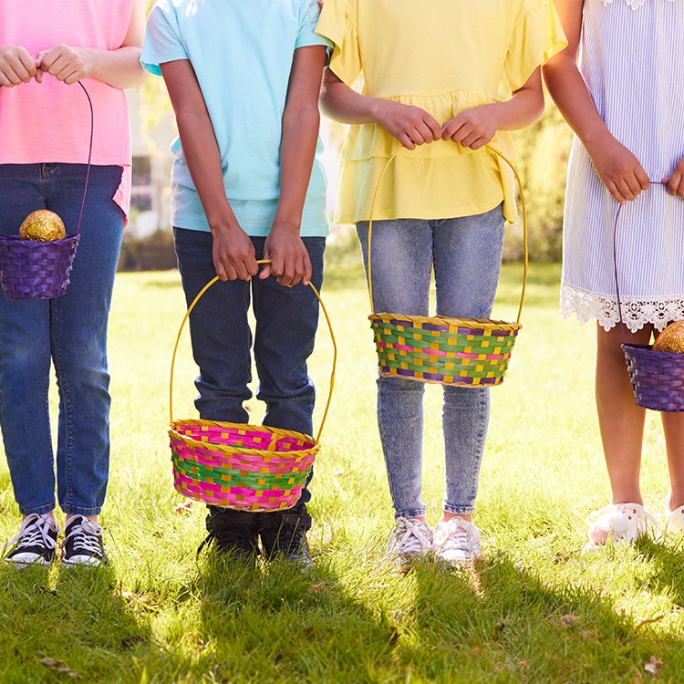 Five children and adults lined up in a park holding Easter baskets