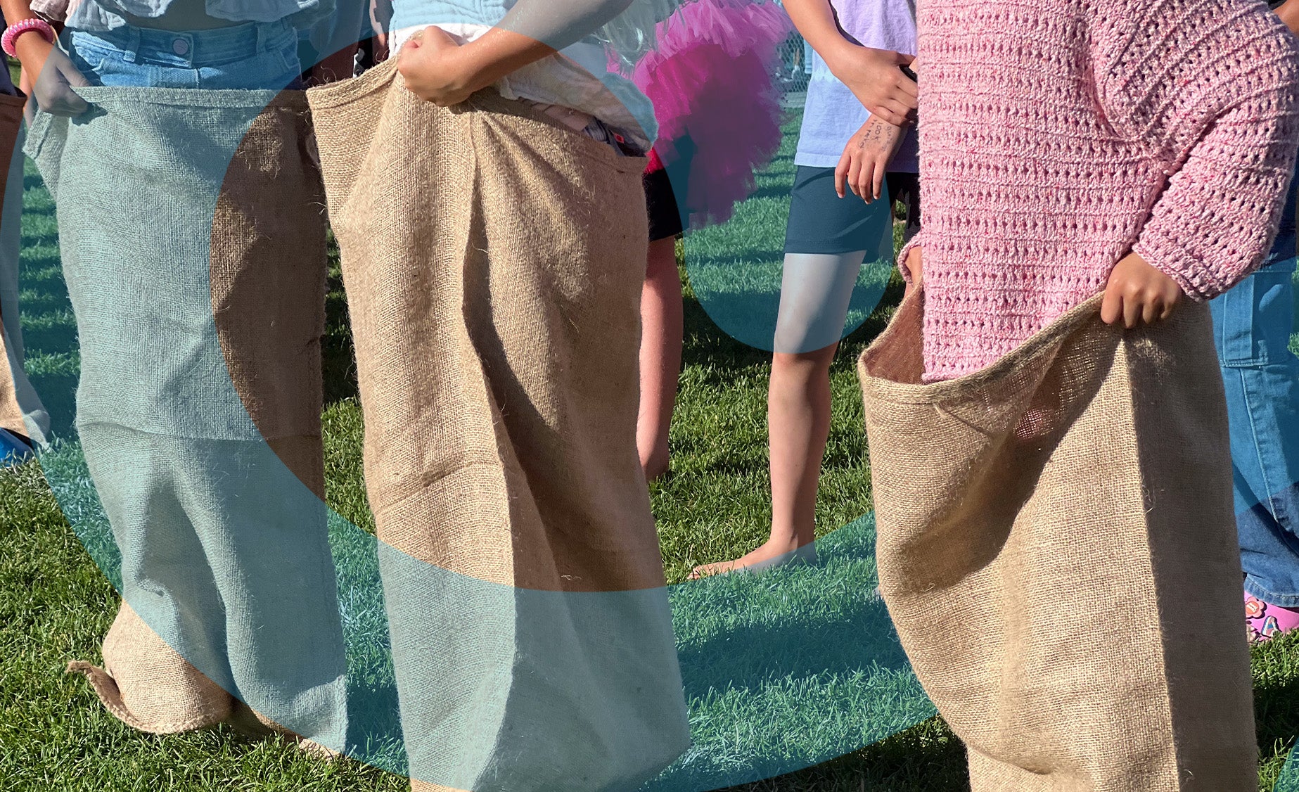 A group of mixed ages lined up on grassland in hessian sacks waiting to play Easter Bunny Hop Race.