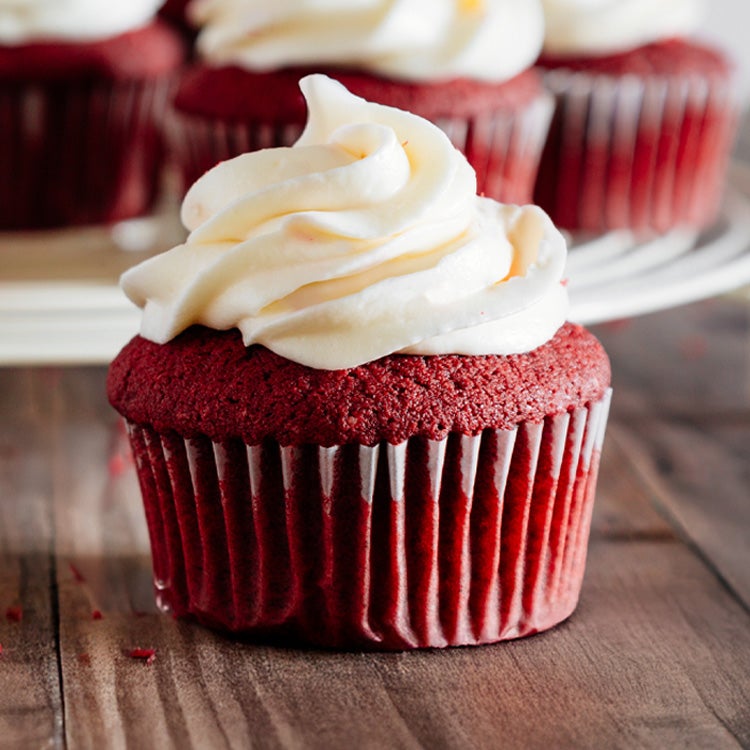 Red velvet cupcakes with Milkybar white chocolate buttercream icing on a wooden board 