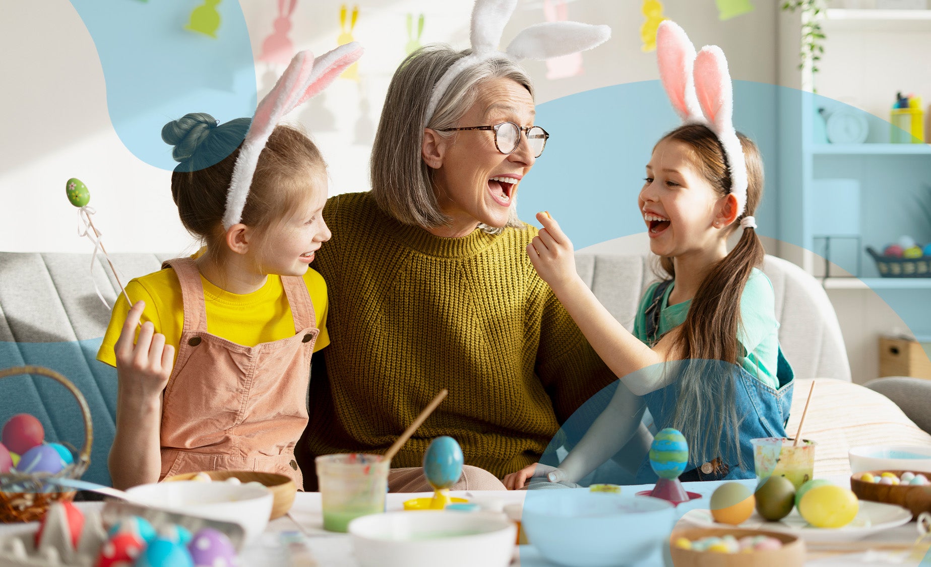 A grandmother with her two daughters wearing bunny ears at a craft table 
