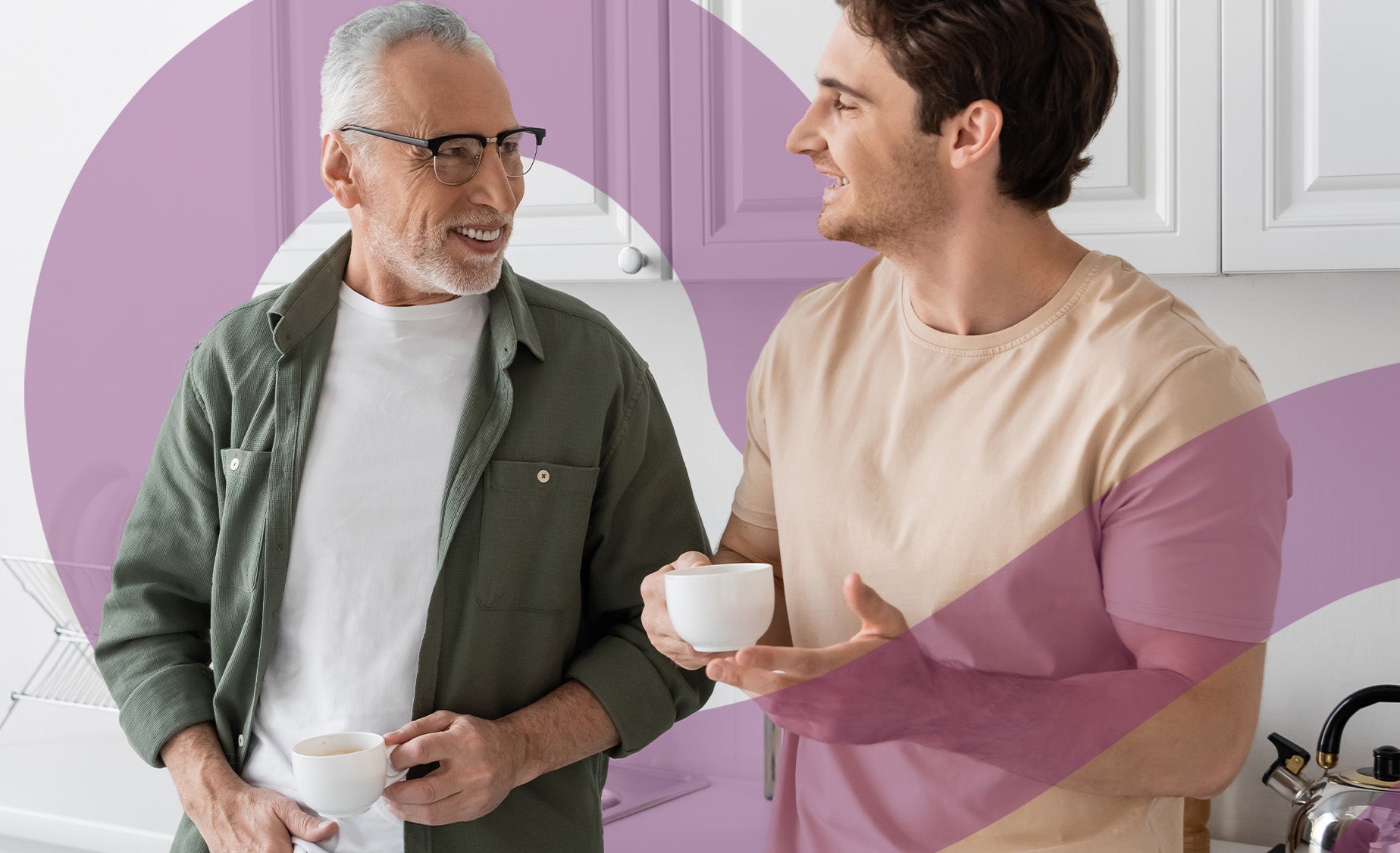 A man shares a coffee with his elderly father in a modern white kitchen 