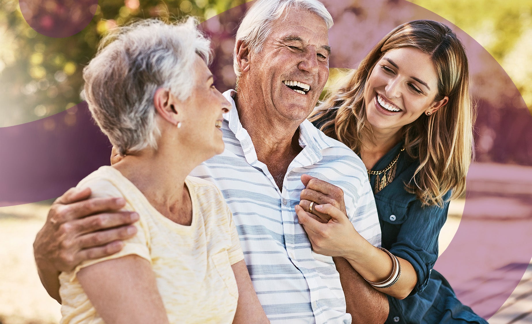 A woman hugs her smiling elderly parents. 