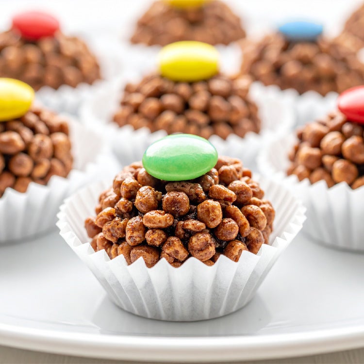 Chocolate Rice Crispy Cakes on a white plate, each with a smartie on top